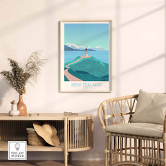 New Zealand travel poster featuring a lighthouse on a hill with mountains and ocean in a stylish room setting.