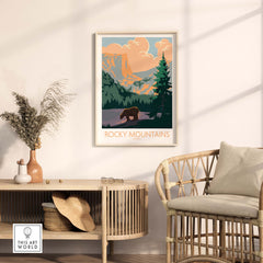 Rocky Mountains Canada poster framed on a wall, featuring a bear and lush green trees in a cozy room setting.